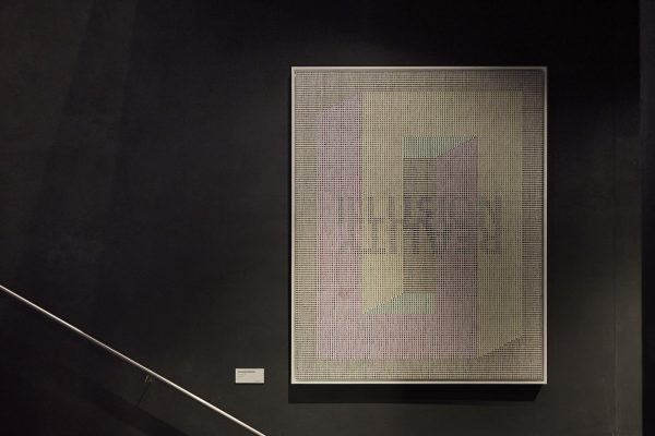 Werk von Marlies Baumgartner, „Illusion of Reality“ (2023): großformatiges Rasterbild aus feinen, farbigen Linien und Punkten, das geometrische Formen in Pastellfarben (Rosa, Gelb, Grün) entstehen lässt; an schwarzer Wand montiert.